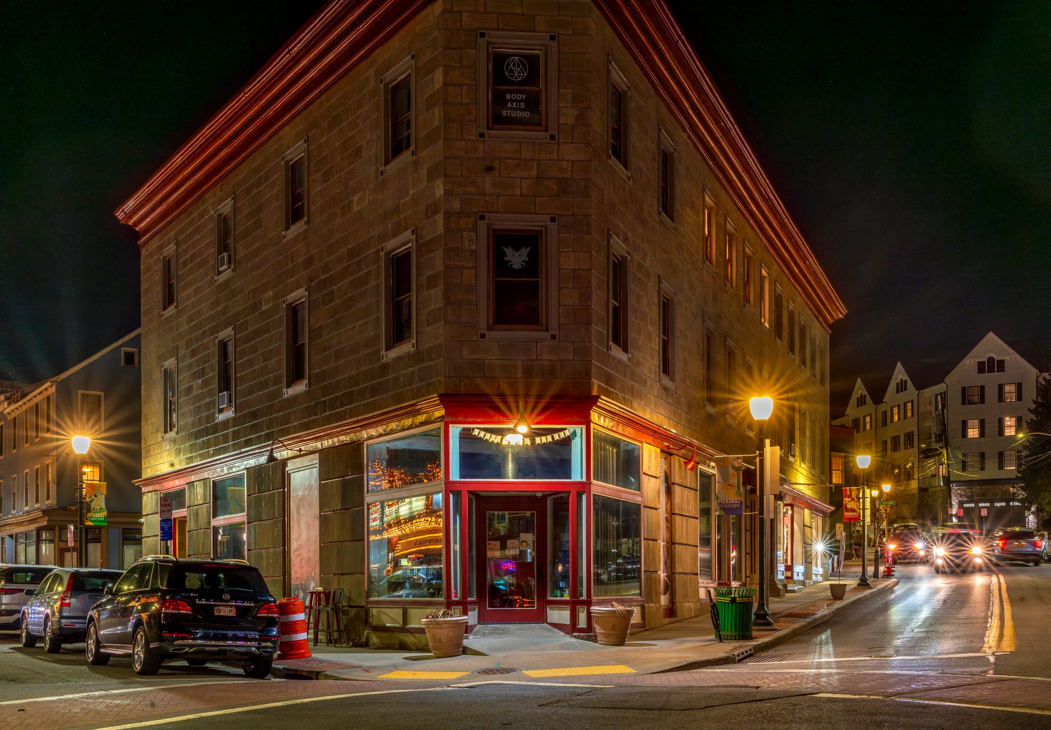 Peekskill, NY - US - Mar 7, 2025 The Peekskill Coffee House, a historic corner building at night, with warm streetlights, reflections of a nearby theater, and a cozy storefront.